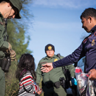 Border Patrol agents surround child.