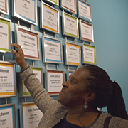 Regina Brown at wall of framed certificates.