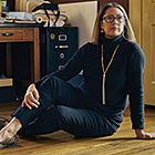 Woman sits on floor at desk.