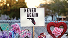 Memorial at fence with sign, Never Again.