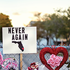 Memorial at fence with sign, Never Again.