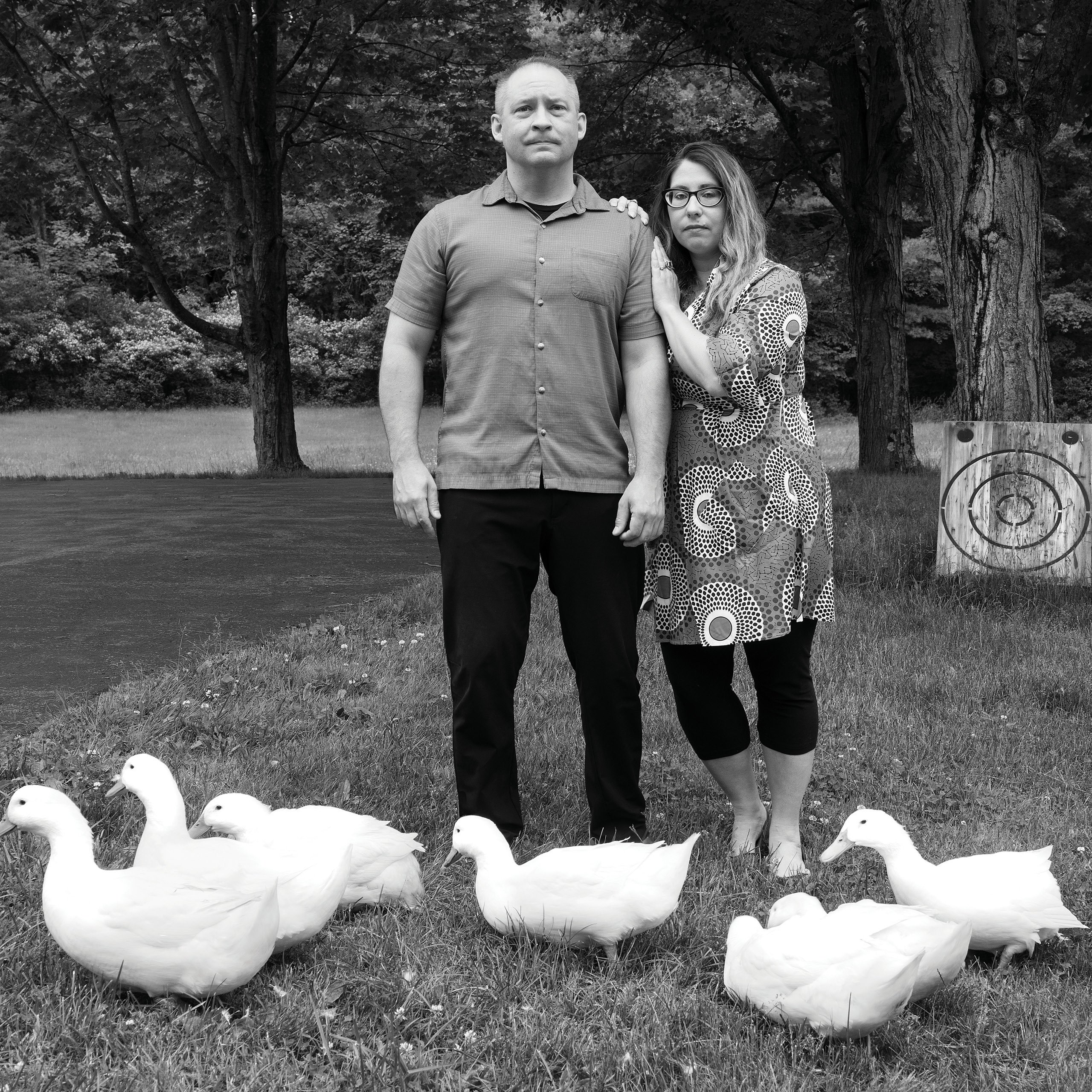 Kate and Dave Kruk stand on a lawn surrounded by fluffy white geese