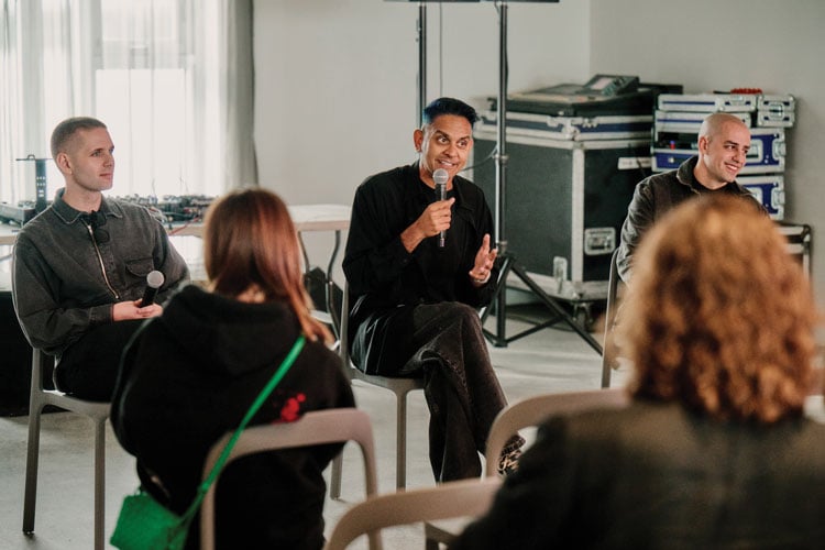 Group of people seated in a circle with a man talking into a microphone