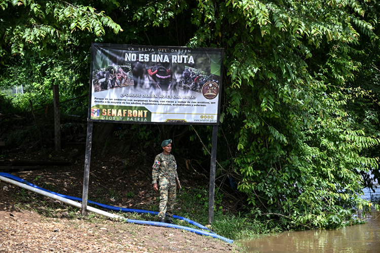 Soldier in the jungle next to a warning sign