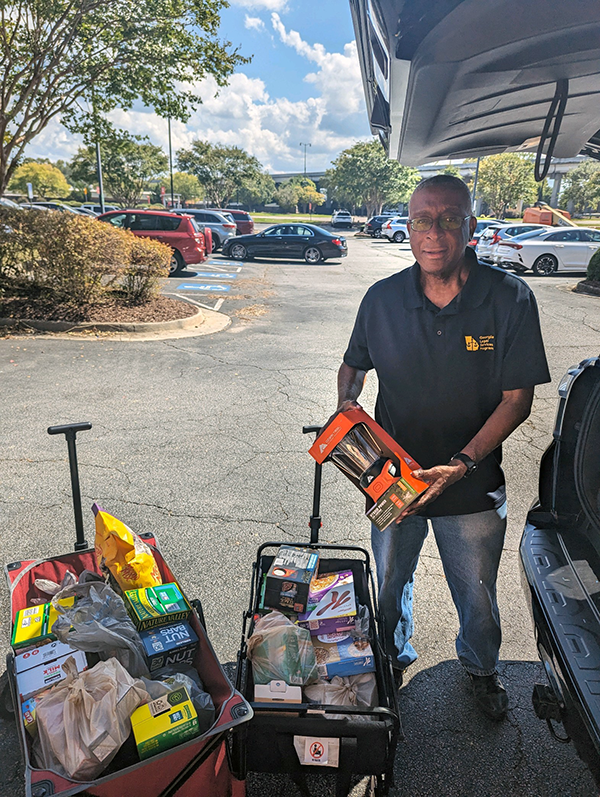 Man posing with supplies next to an SUV