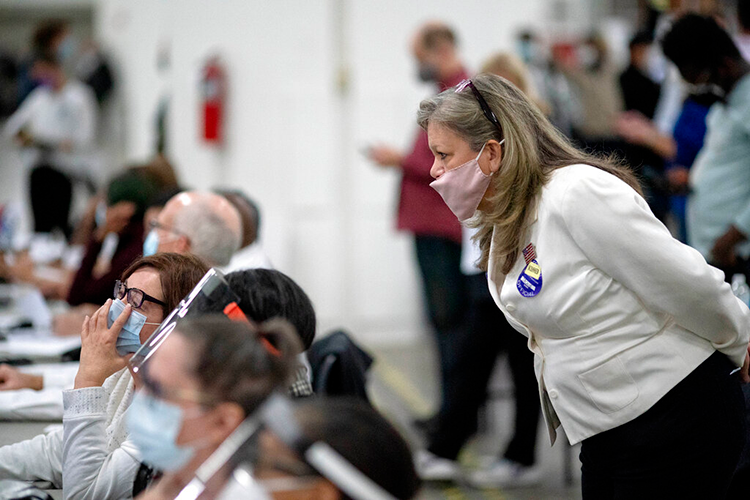 Woman looks over the shoulder of election workers