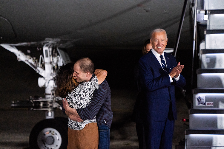 Man hugging a woman next to the president in front of an airplane