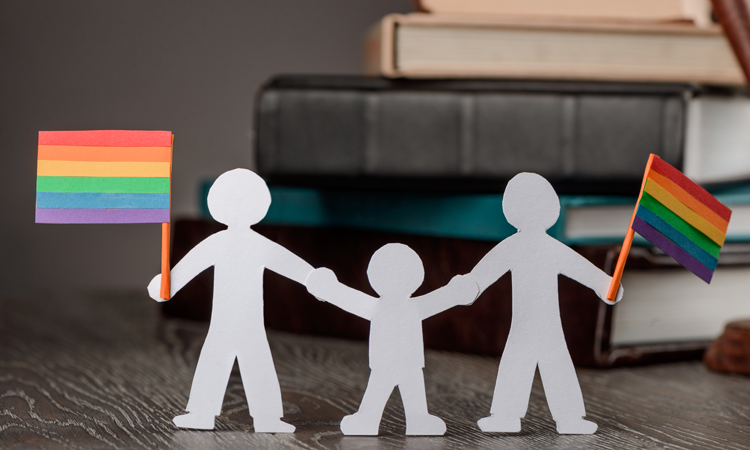 Paper doll family with rainbow flags in front of law books