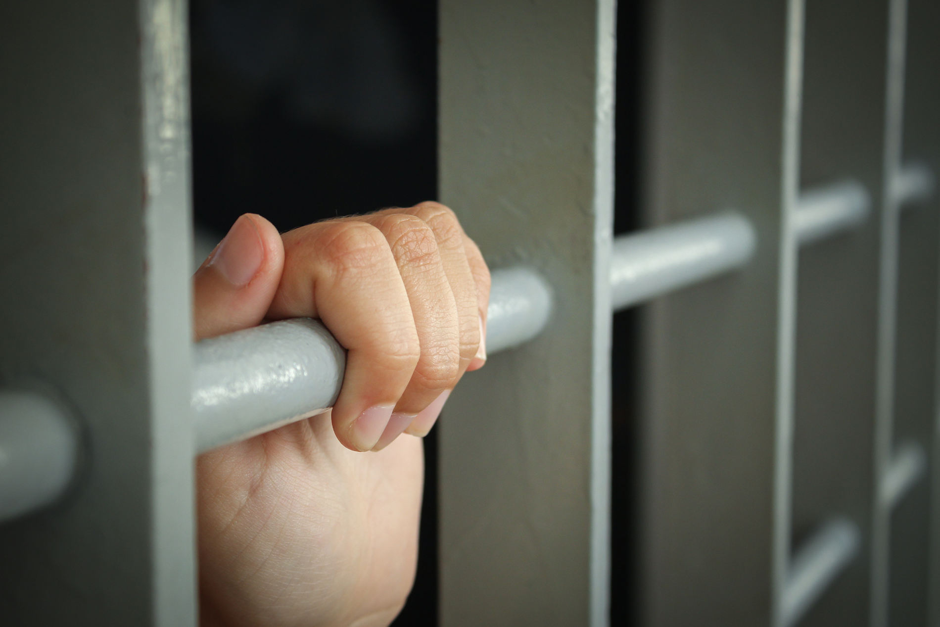 A woman's hand gripped around a prison bar