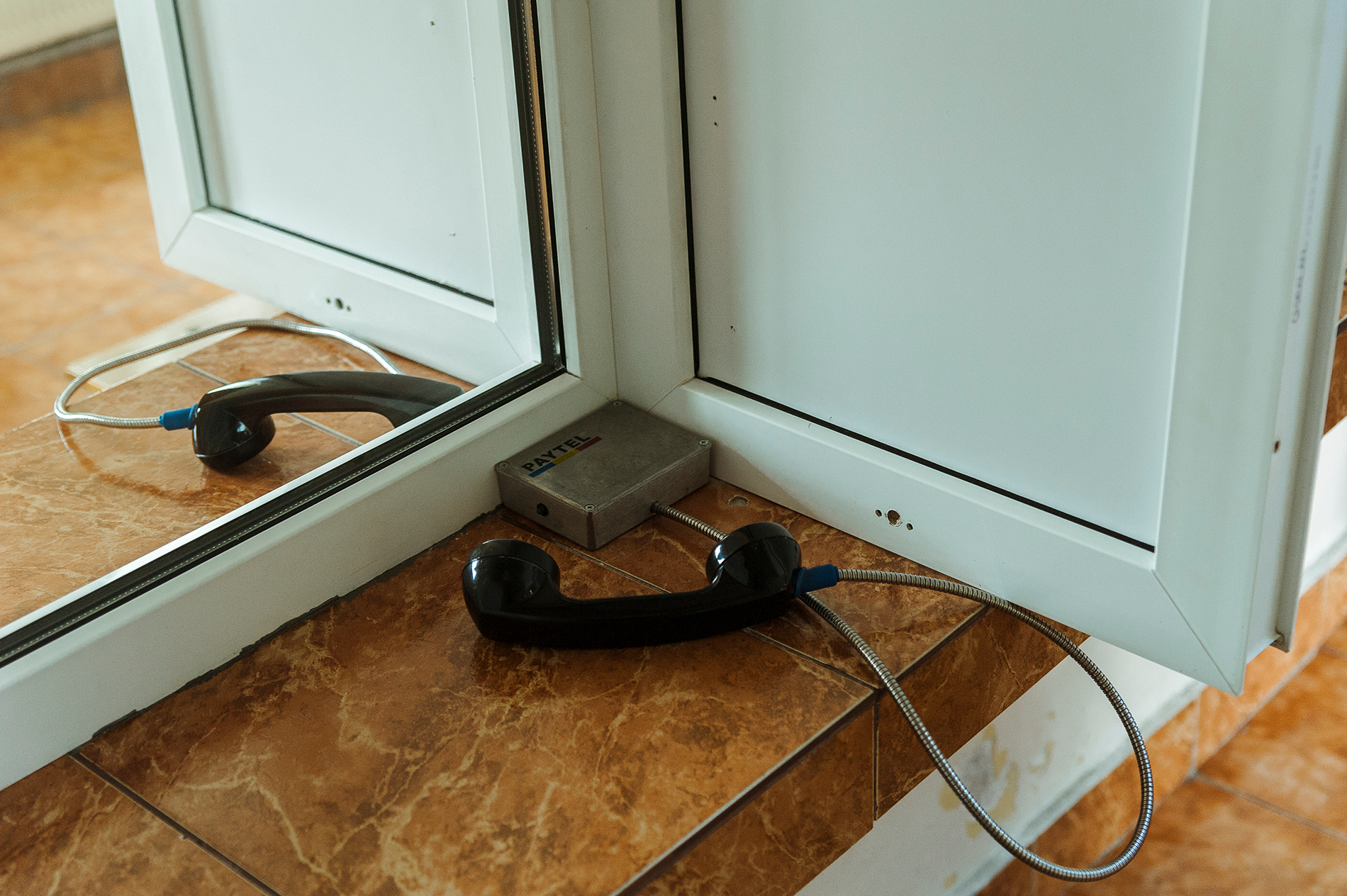 A prison visiting room with phones separated by plexiglass