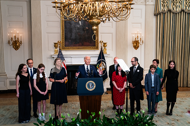 President at a podium flanked by a line of other people